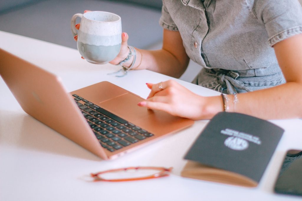 Social Media Management 1 A woman sitting at a table with a laptop and a cup of coffee